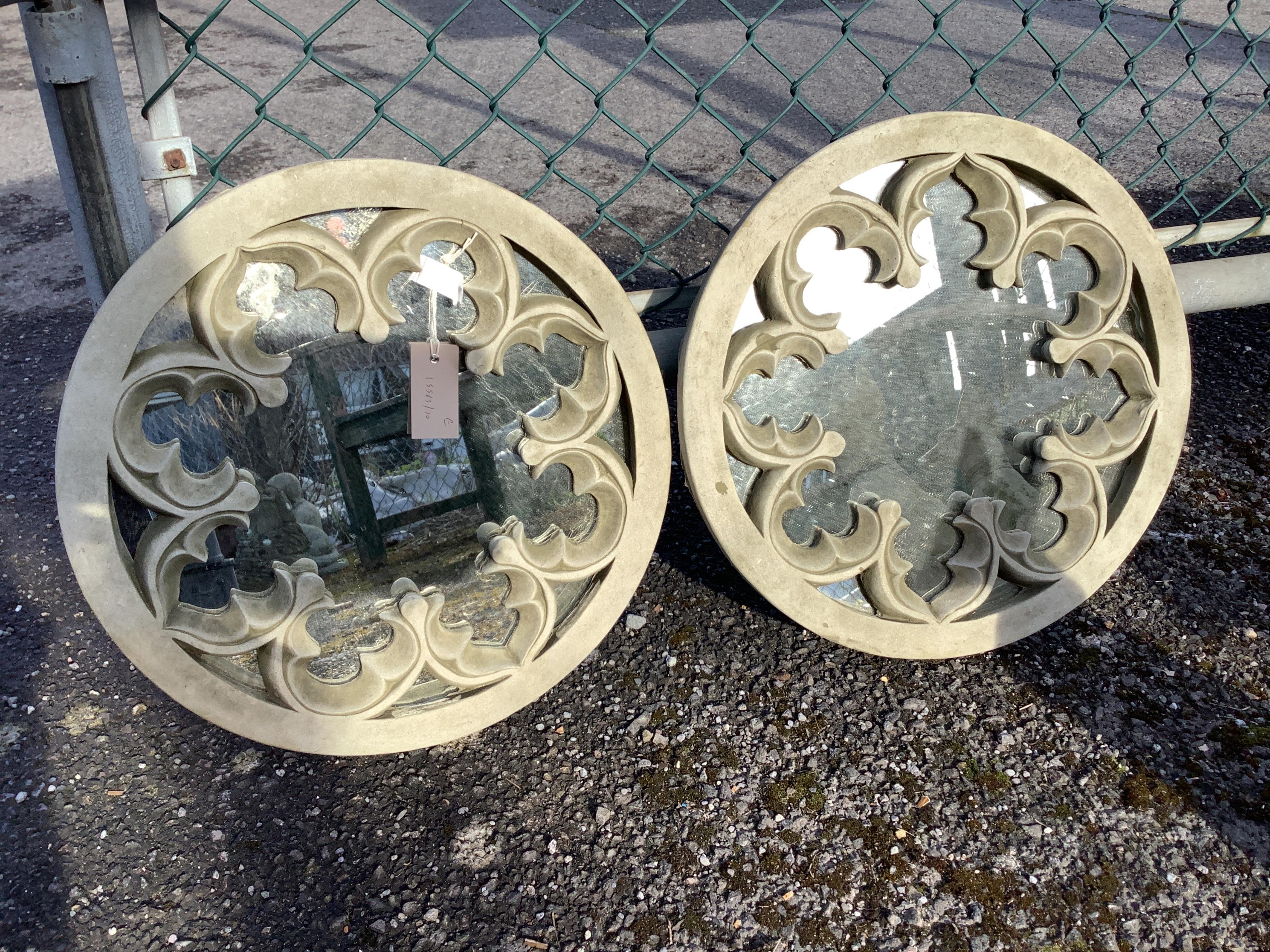 A pair of reconstituted stone wall mirrors of Gothic roundel form, diameter 44cm. Condition - weathered, otherwise good